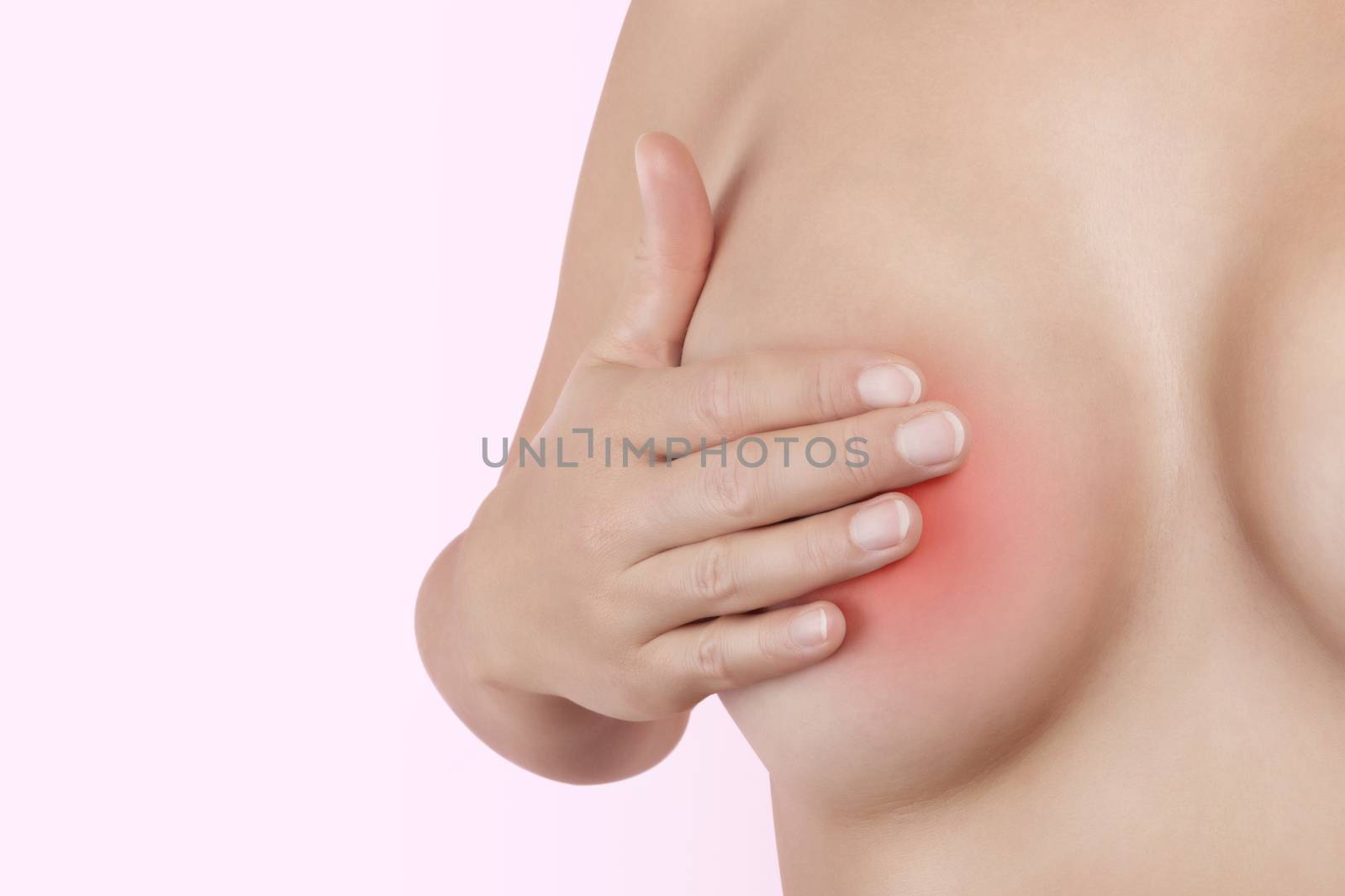 Breast self examination. Beautiful young woman touching her breast isolated on pink background. Sensual feminine beauty and health. Breast cancer.