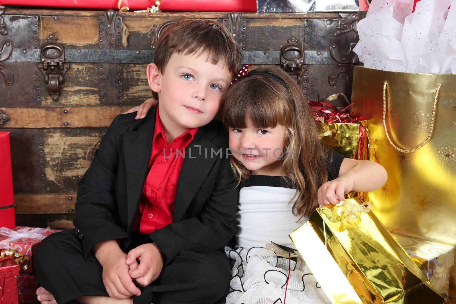 Beautifully dressed brother and sister opening christmas gifts