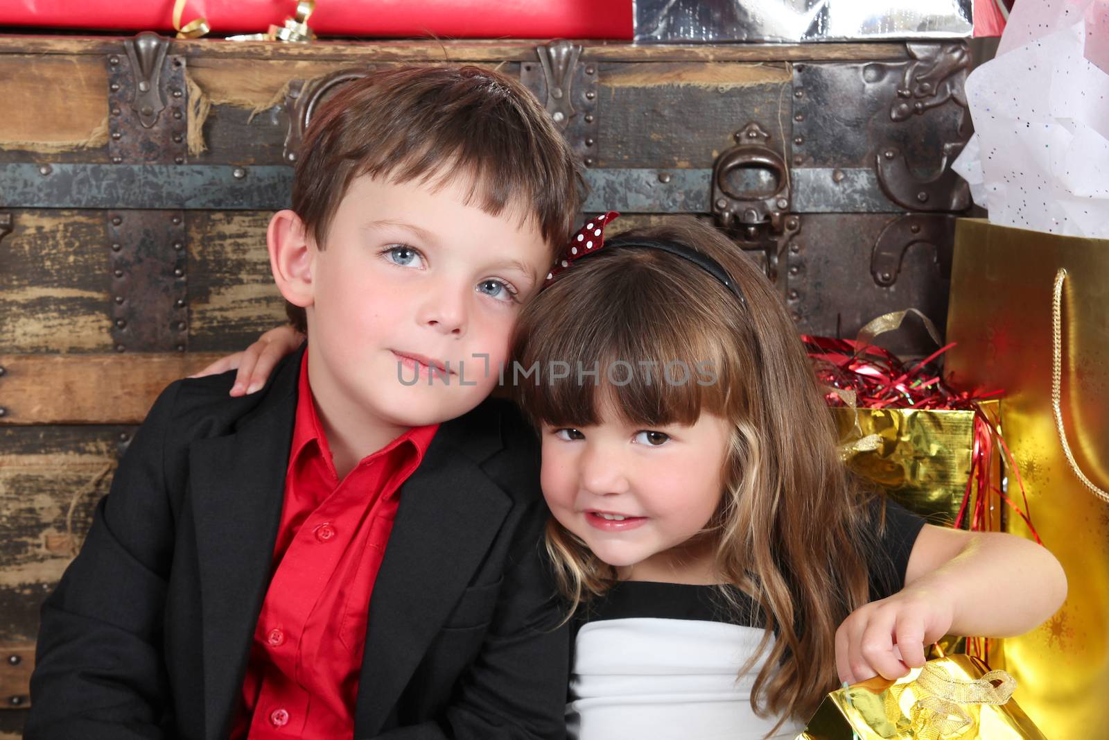 Beautifully dressed brother and sister opening christmas gifts