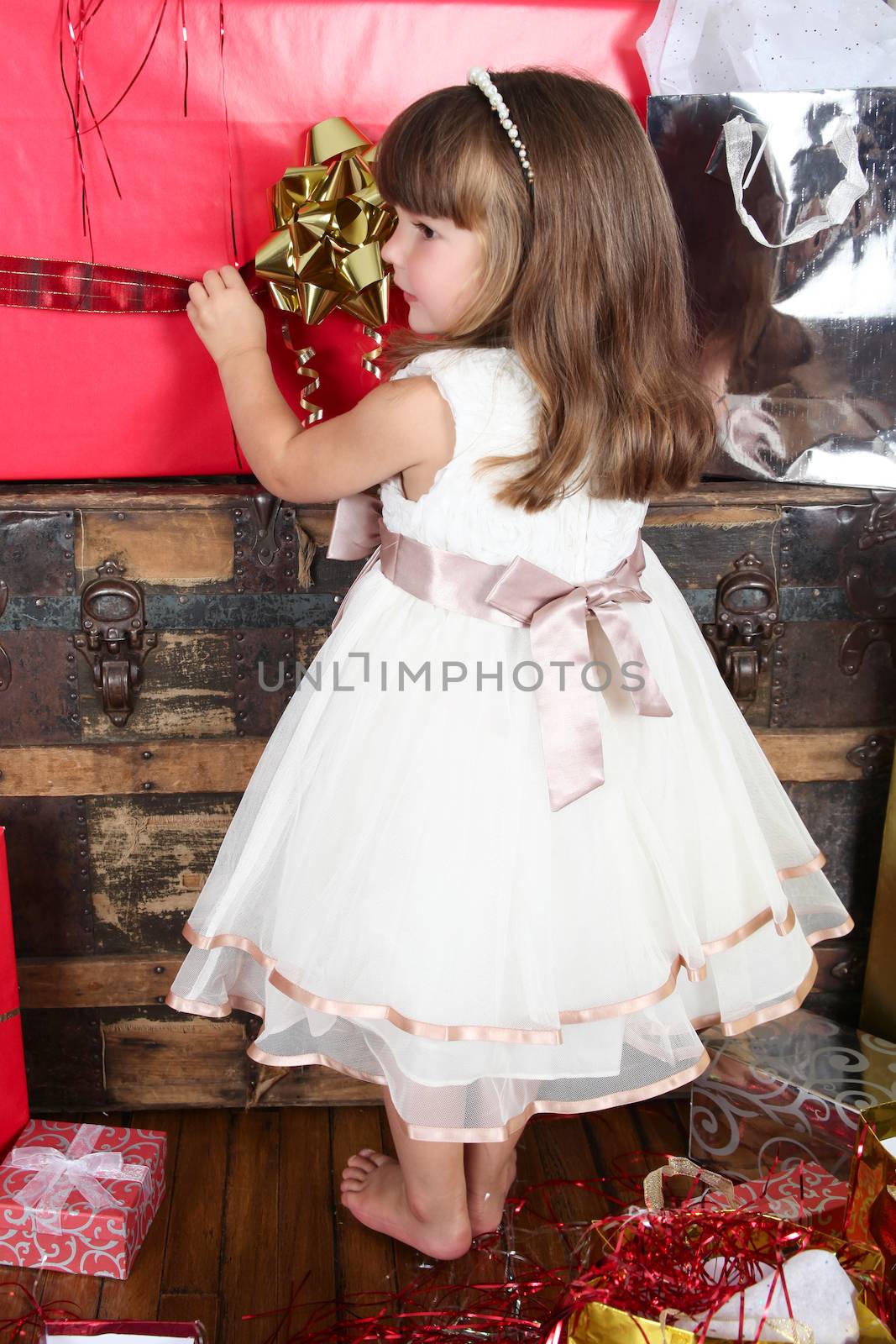Little girl in a dress opening christmas gifts