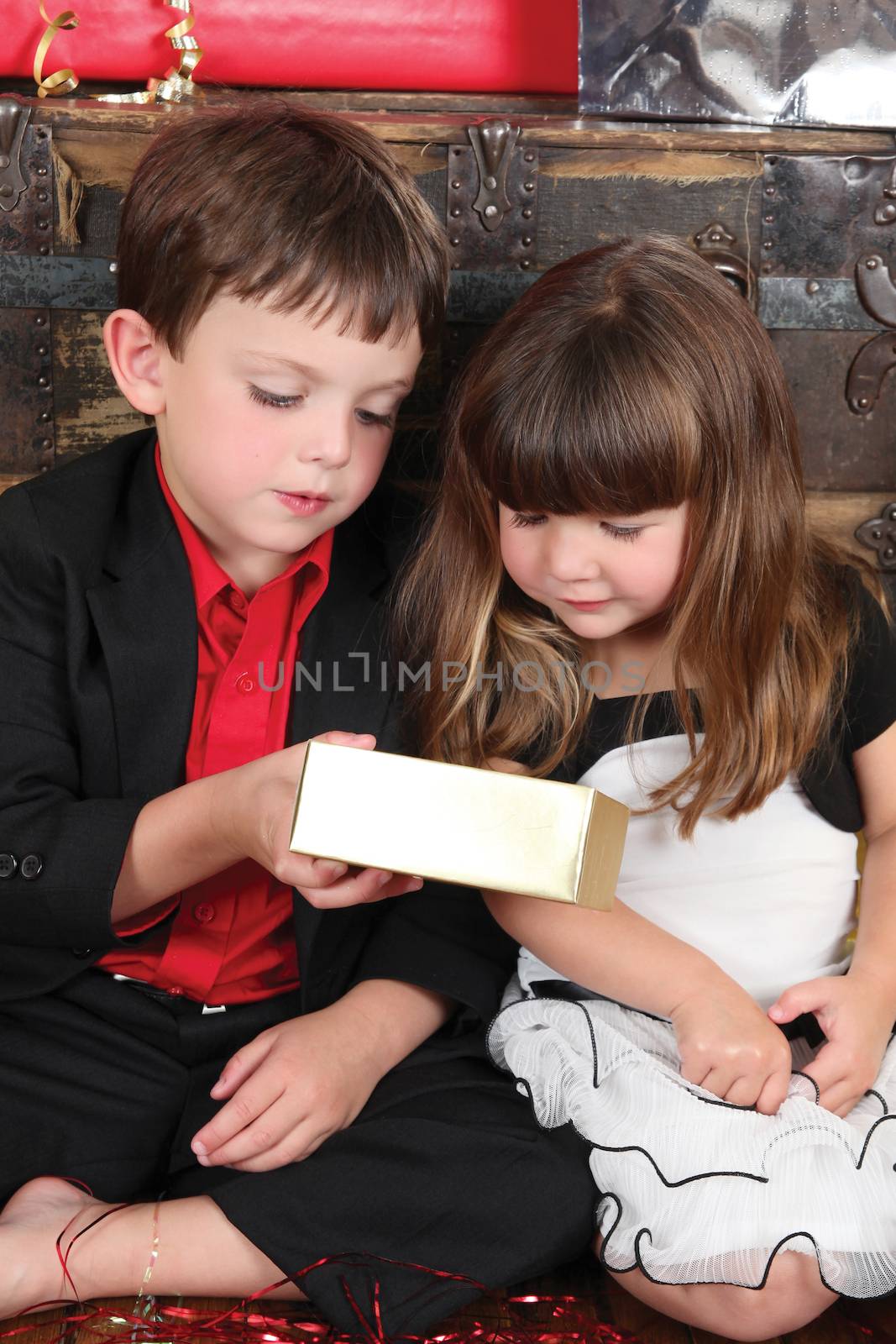 Beautifully dressed brother and sister opening christmas gifts