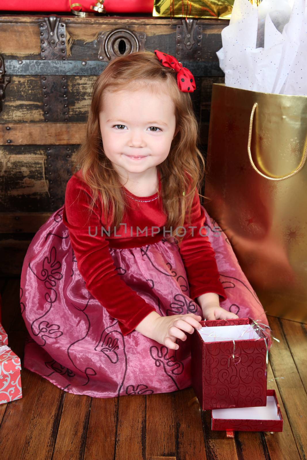 Little girl in a dress opening christmas gifts