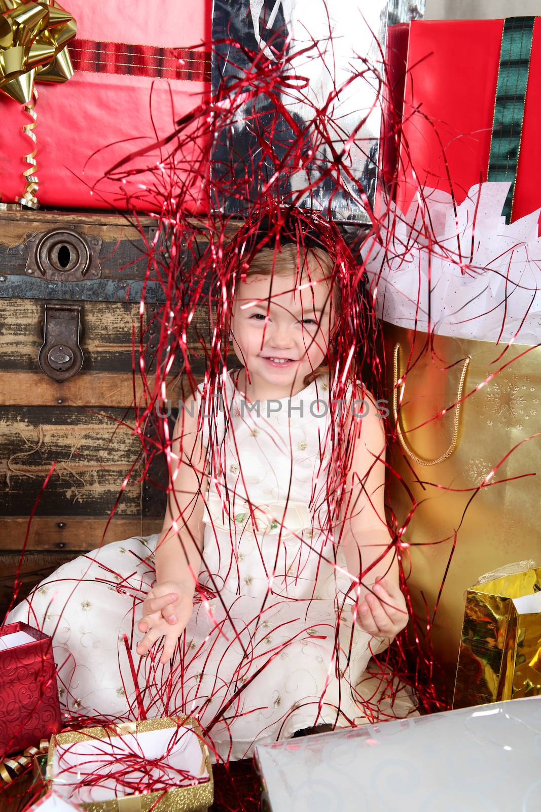 Little girl in a dress opening christmas gifts