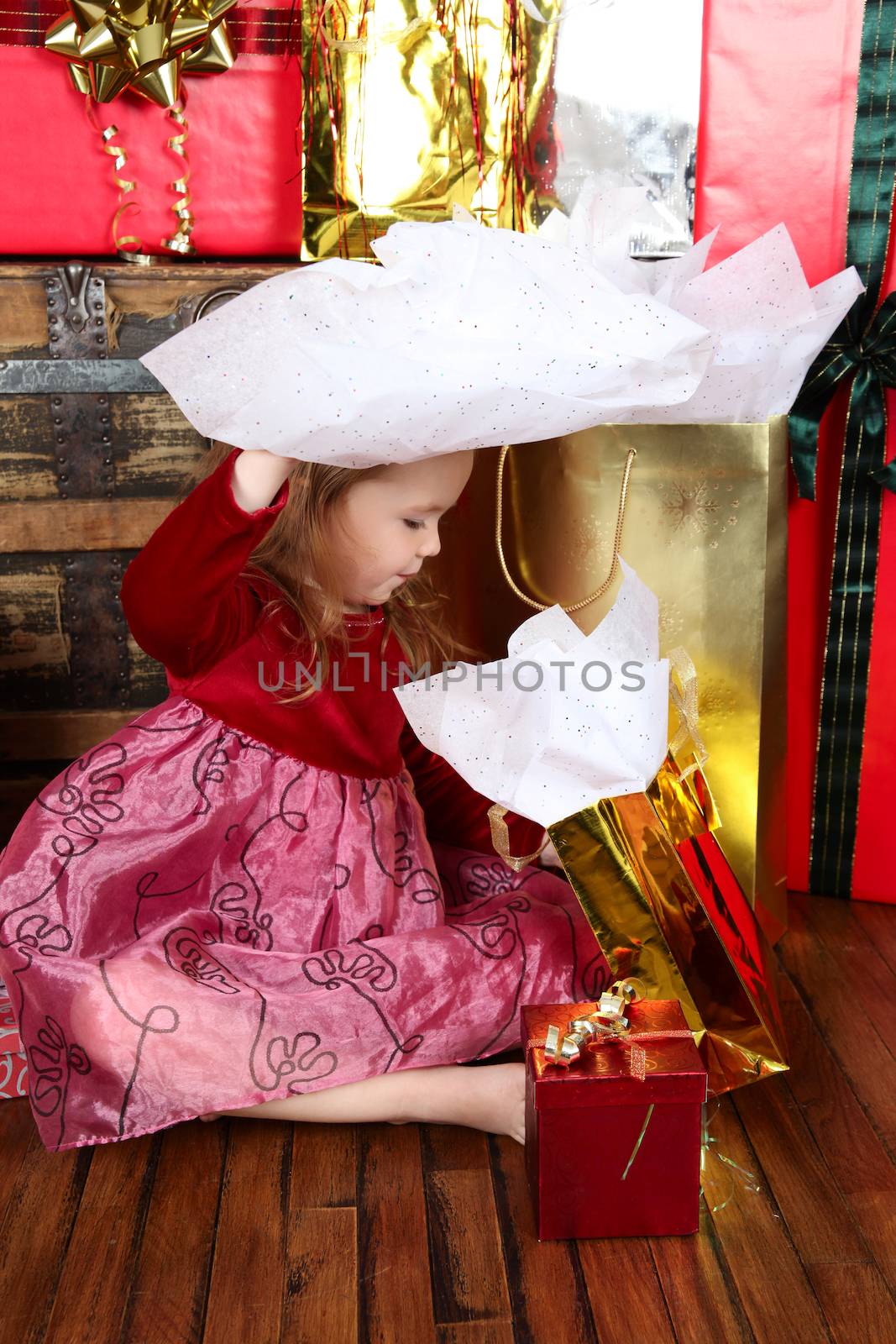 Little girl in a dress opening christmas gifts