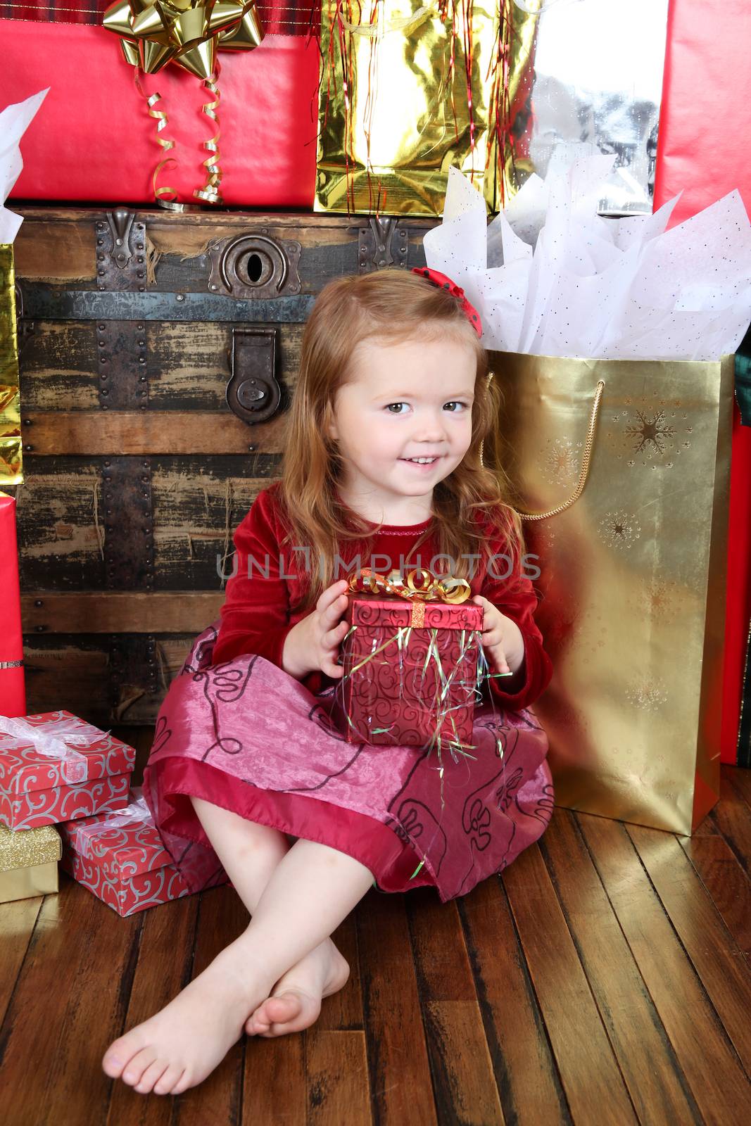 Little girl wearing a christmas dress looking at gifts