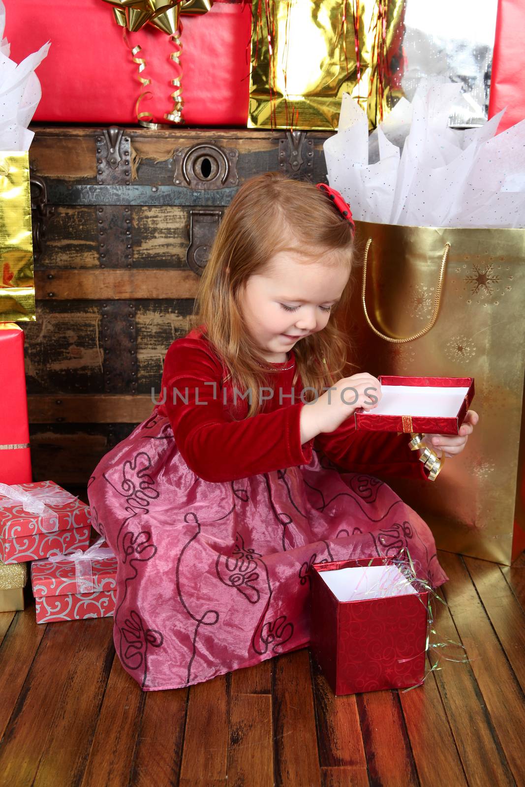 Little girl wearing a christmas dress looking at gifts
