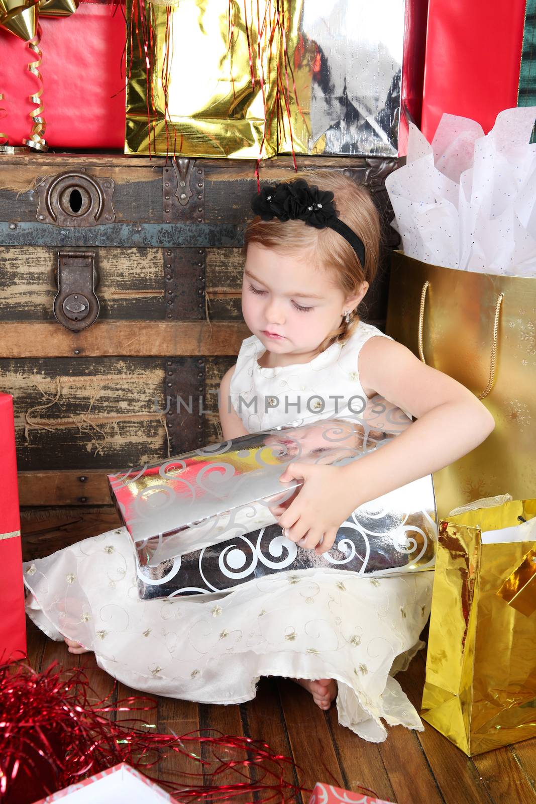 Little girl wearing a christmas dress looking at gifts