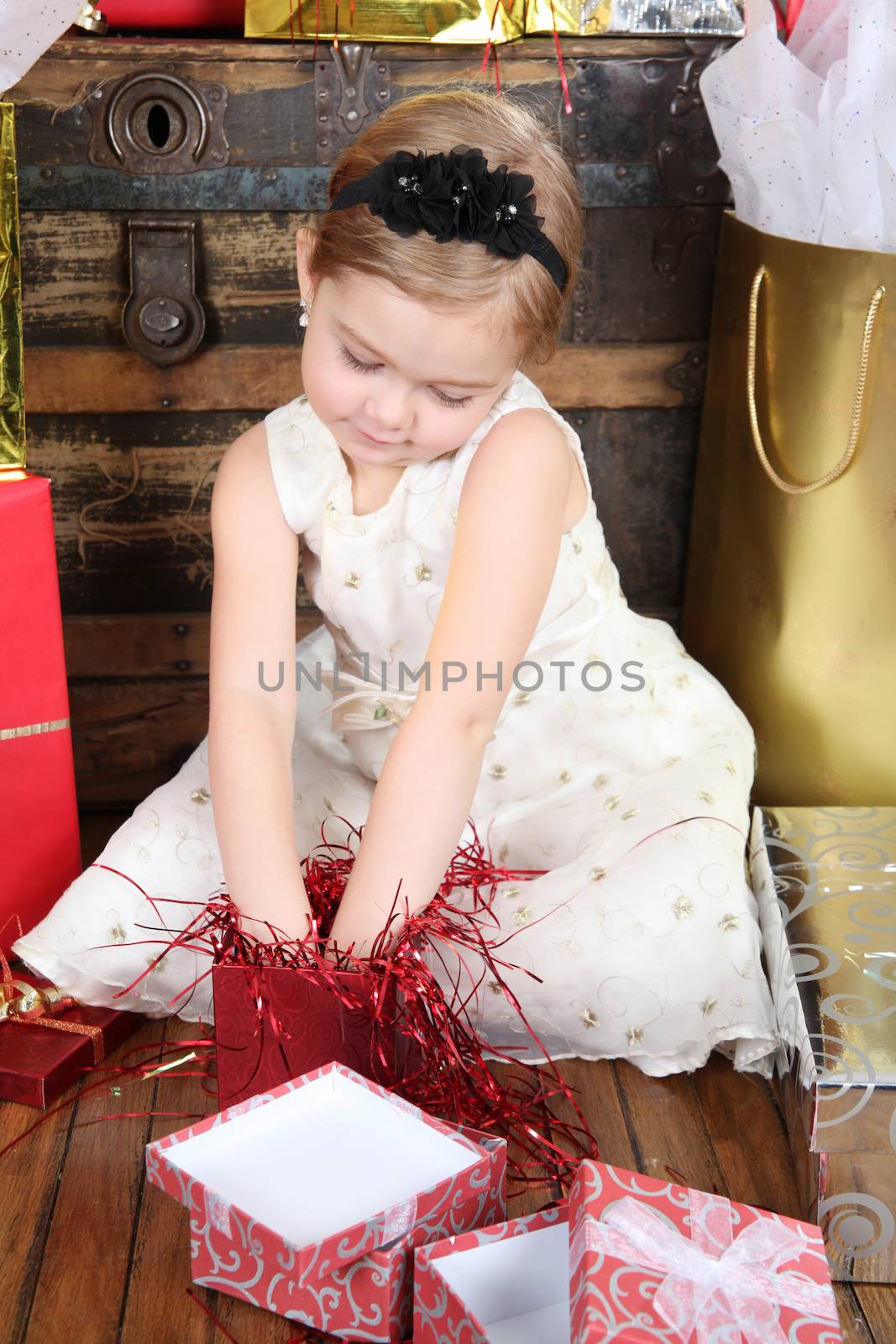 Little girl wearing a christmas dress looking at gifts