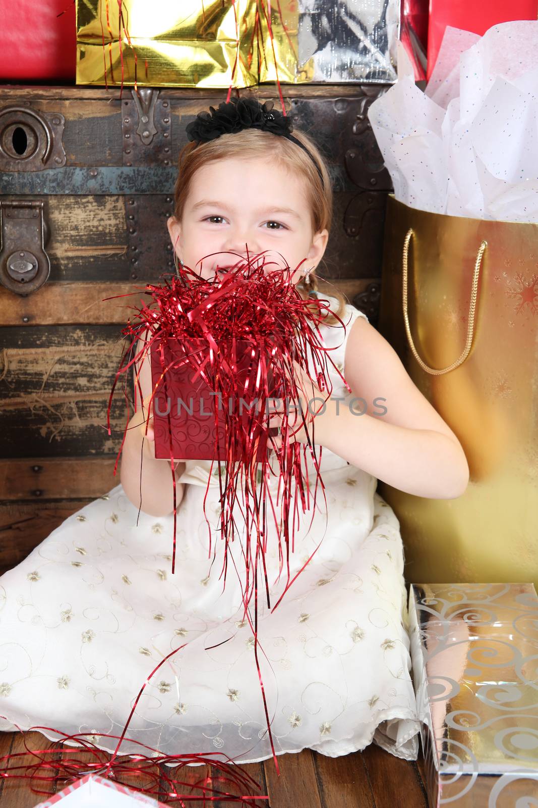 Little girl wearing a christmas dress looking at gifts