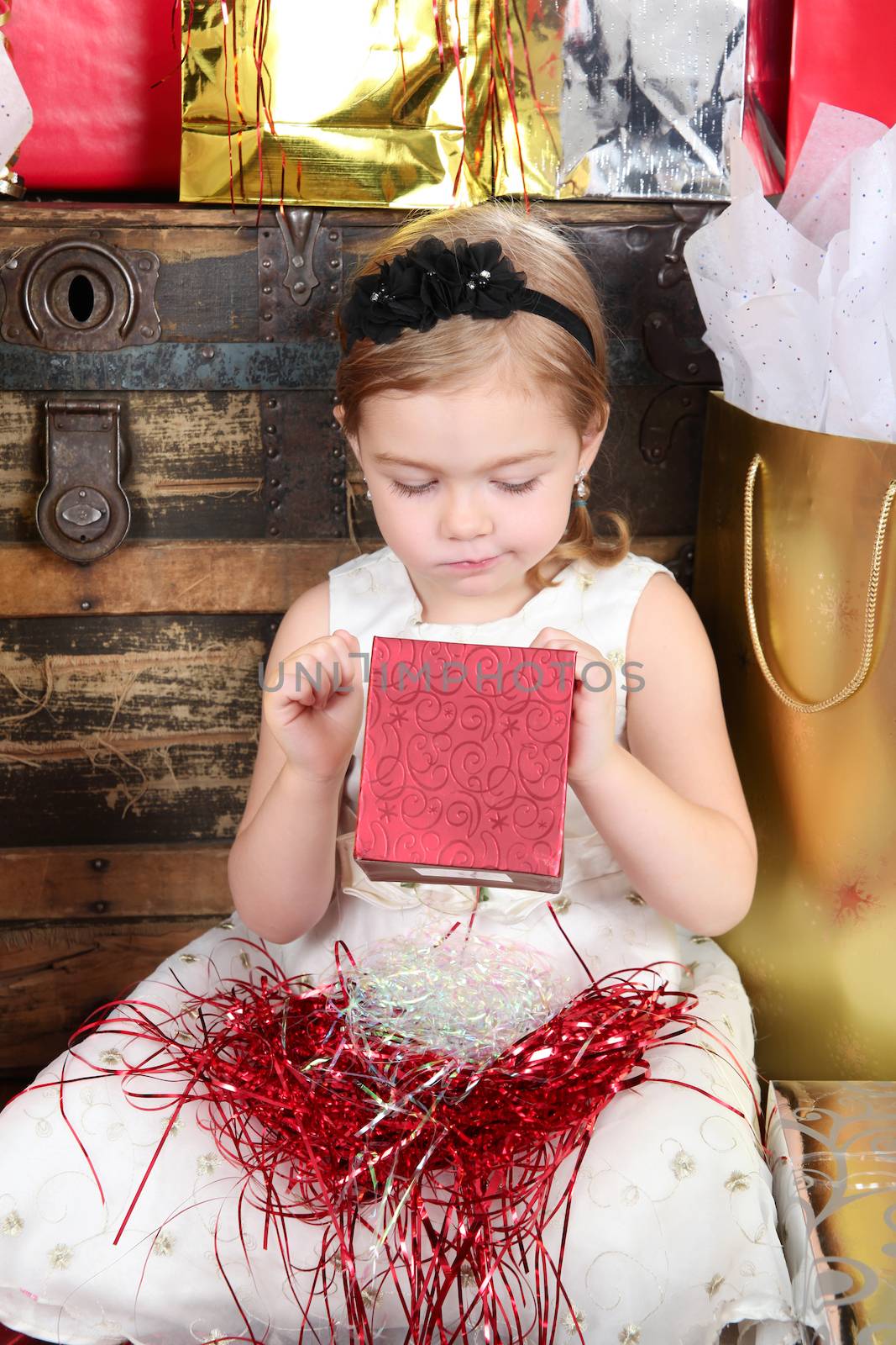 Little girl wearing a christmas dress looking at gifts