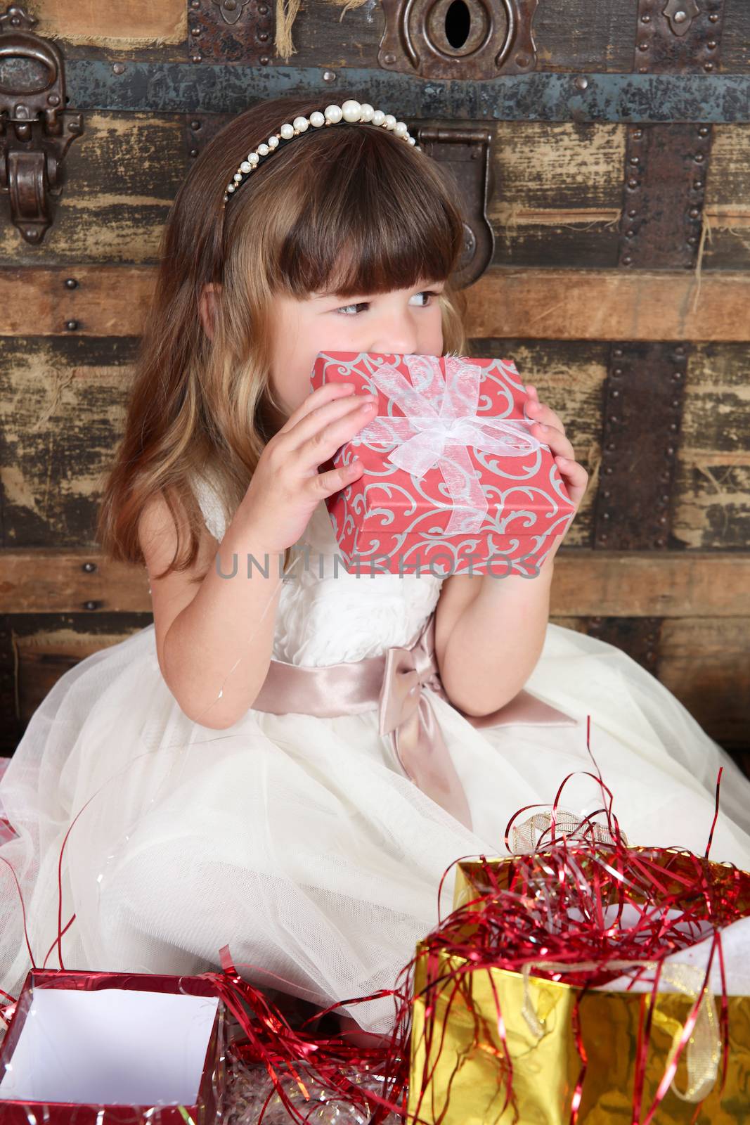 Little girl wearing a christmas dress looking at gifts