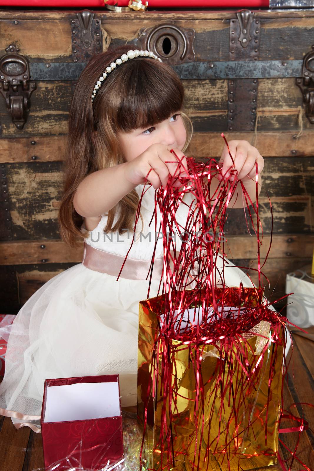 Little girl wearing a christmas dress looking at gifts