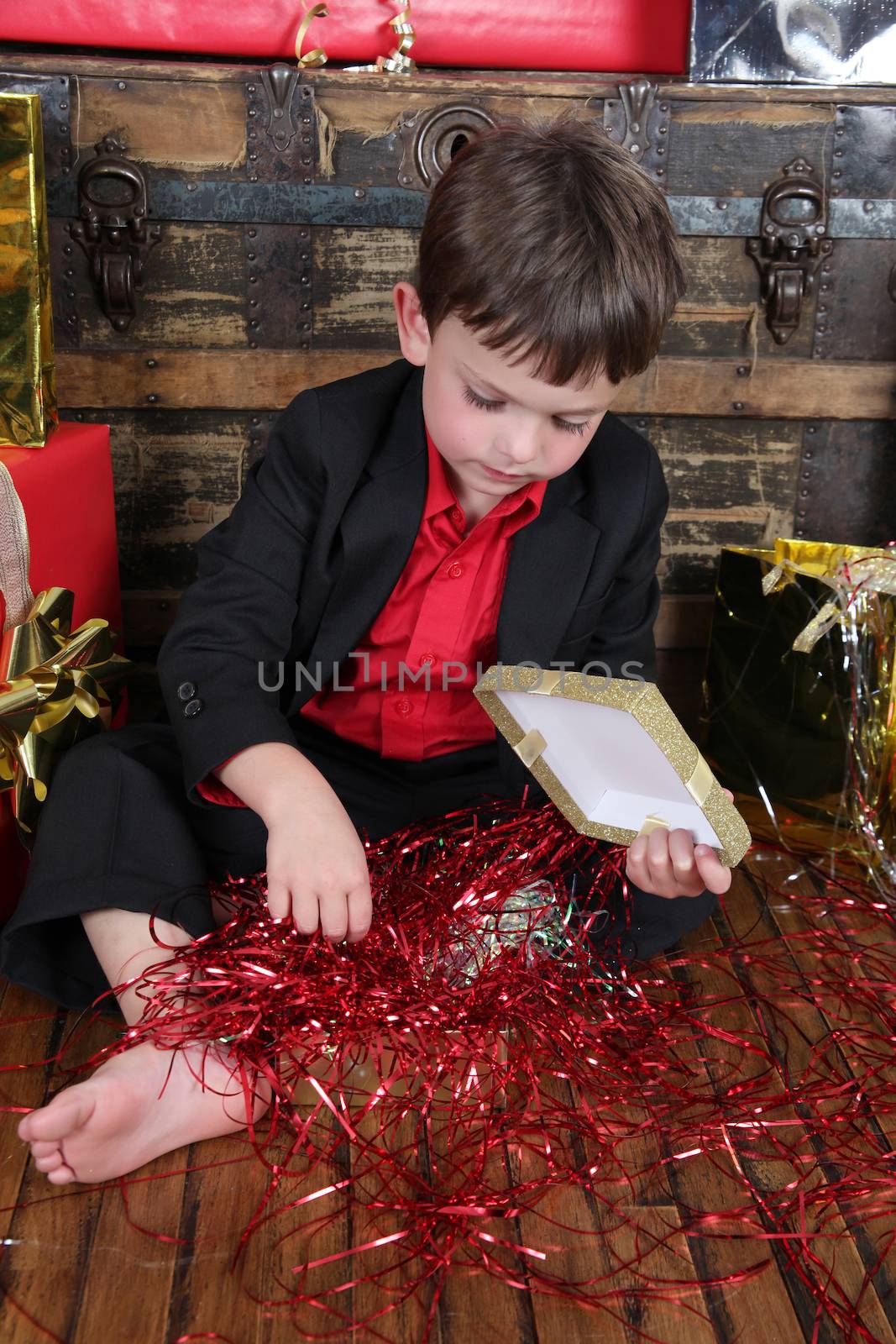 Little boy wearing a christmas suit looking at gifts