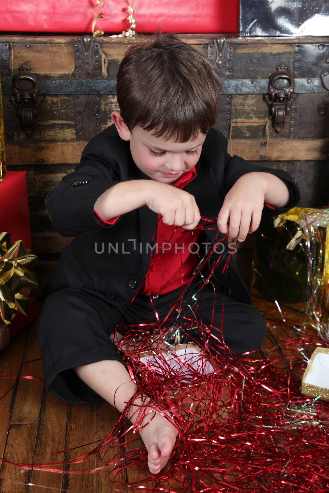 Little boy wearing a christmas suit looking at gifts