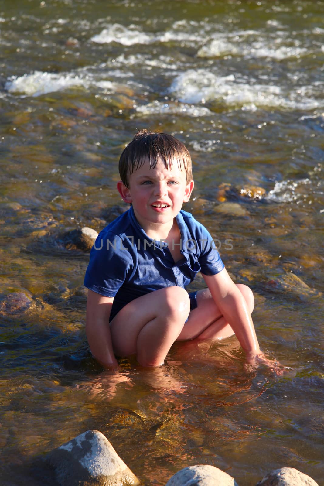 Little boy playing outside in a stream of water