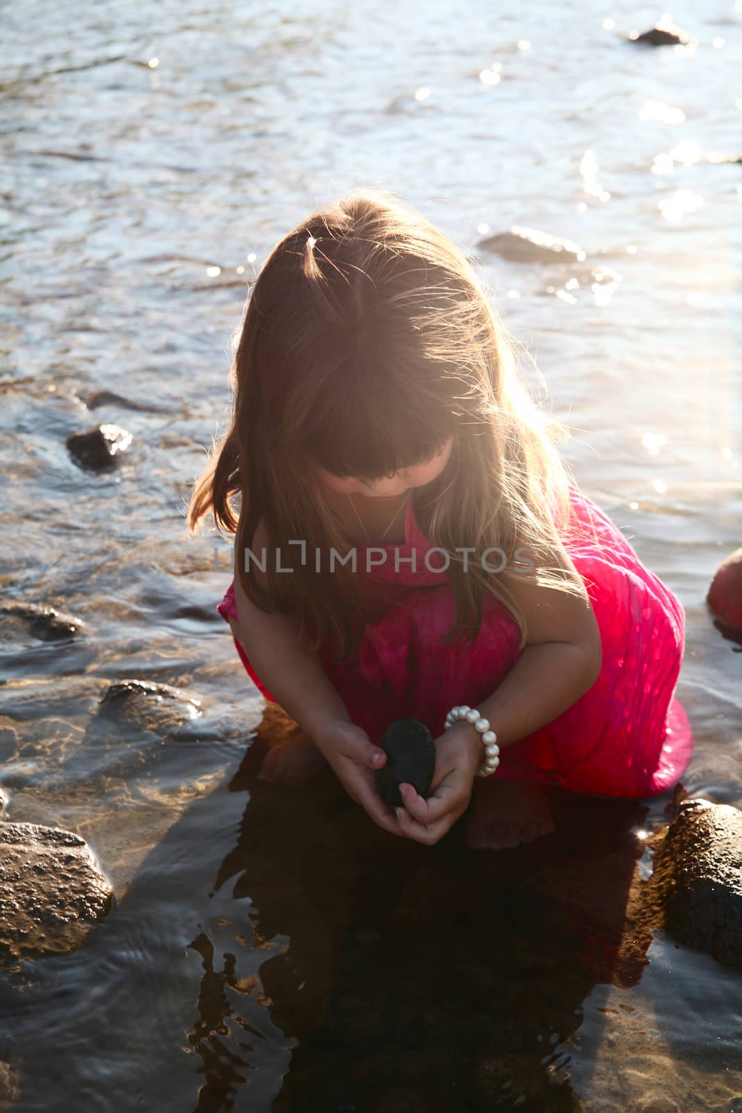 Little girl playing in a shallow stream of water