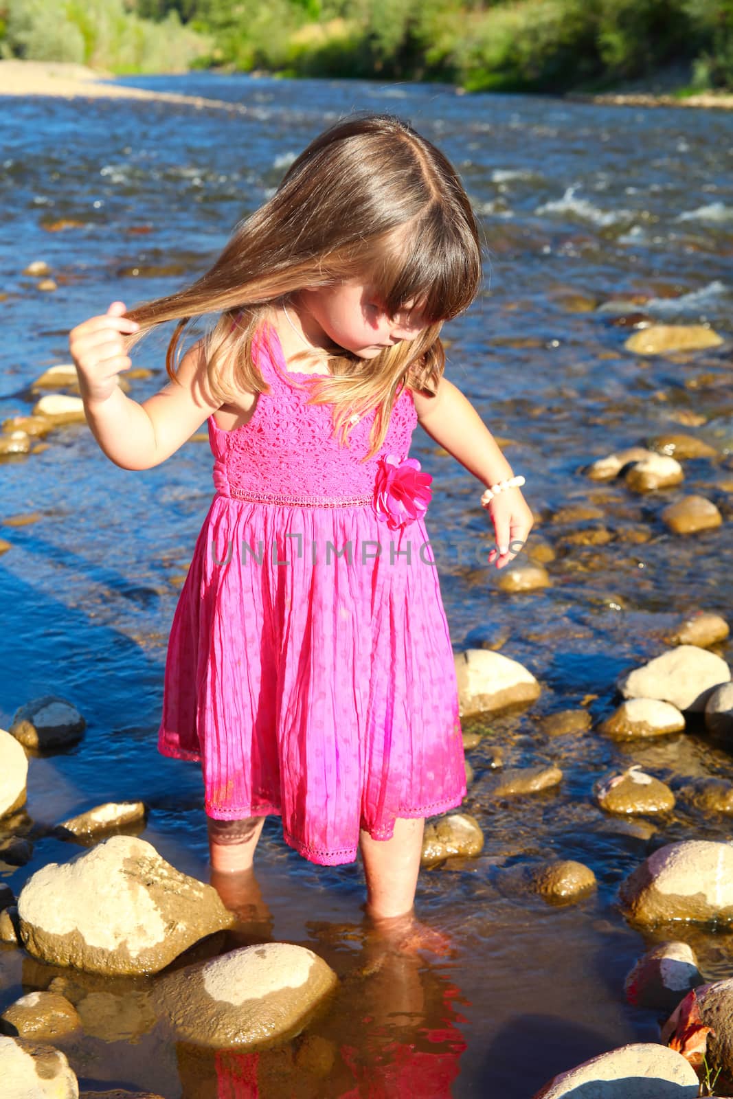 Little girl playing in a shallow stream of water