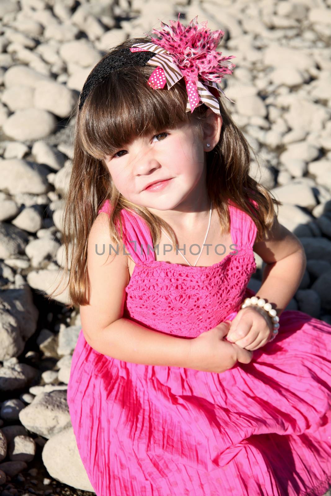 Little girl playing at pebble beach on summer day