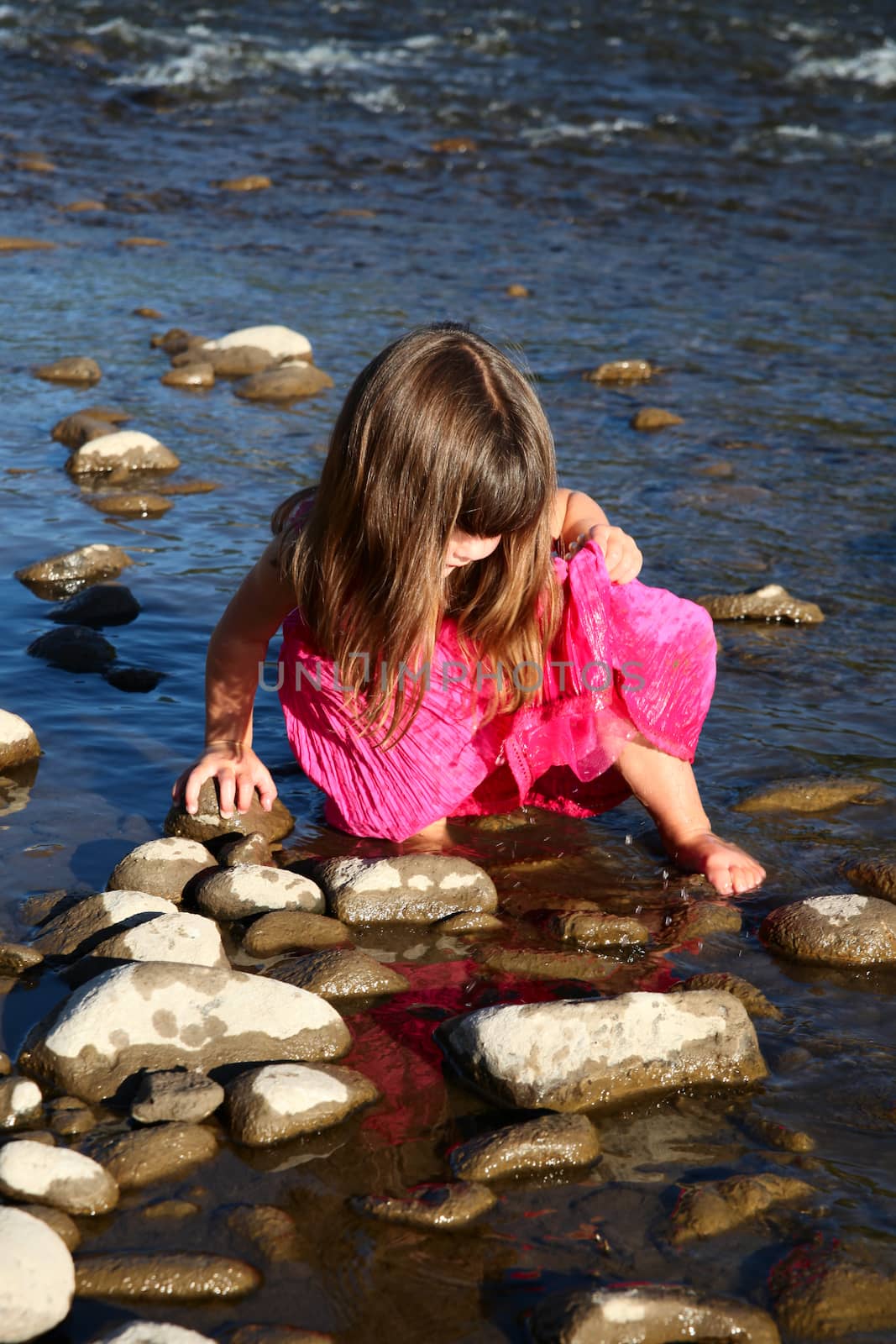 Little girl playing in a shallow stream of water