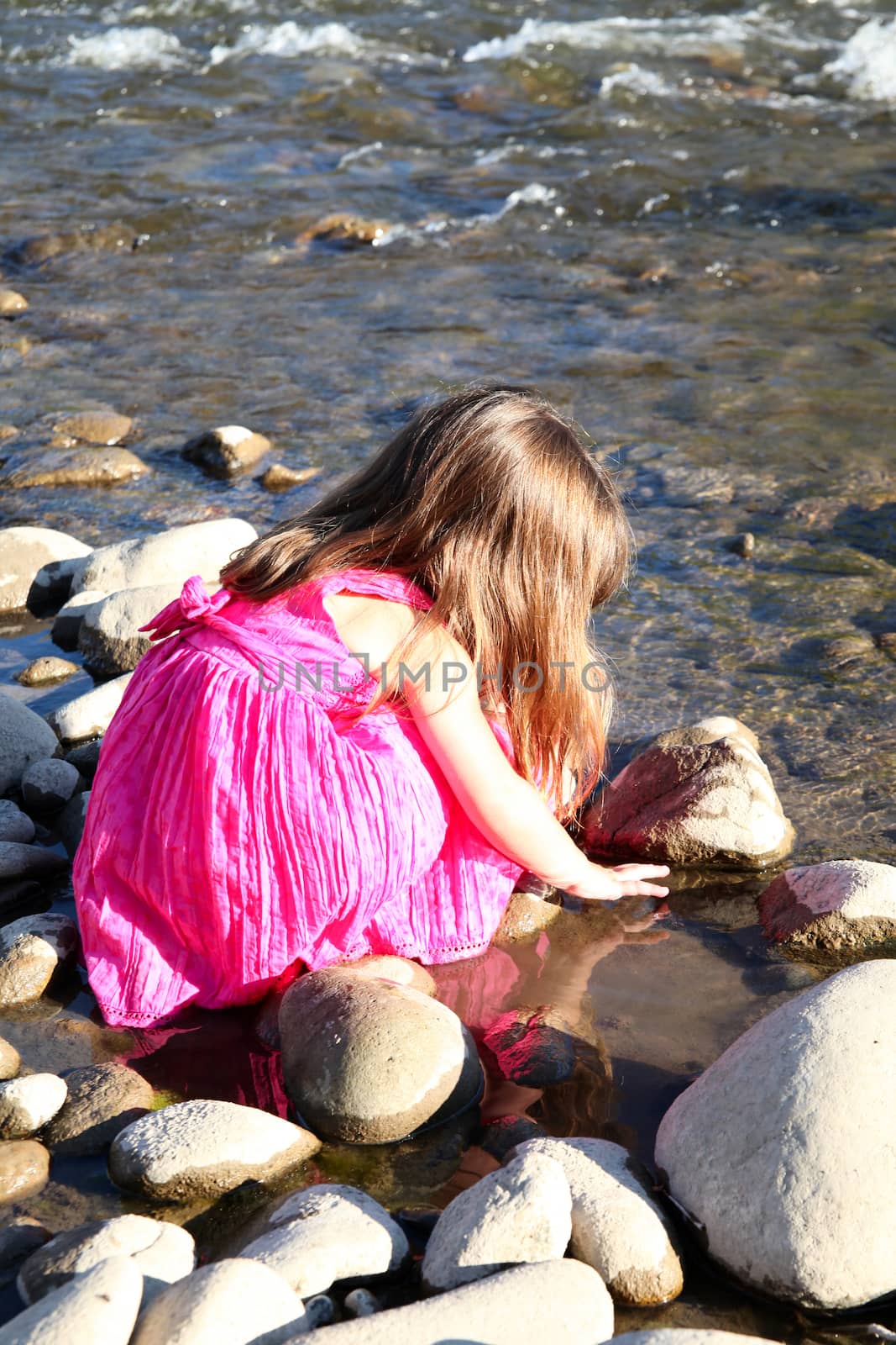 Little girl playing in a shallow stream of water