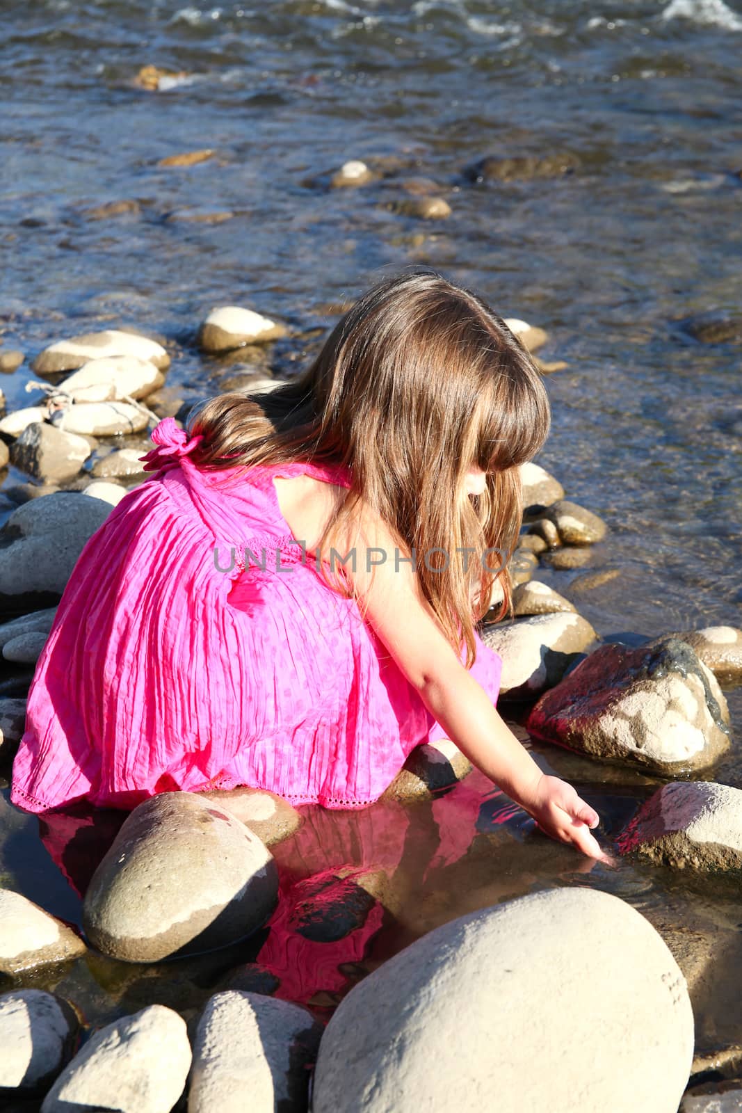 Little girl playing in a shallow stream of water