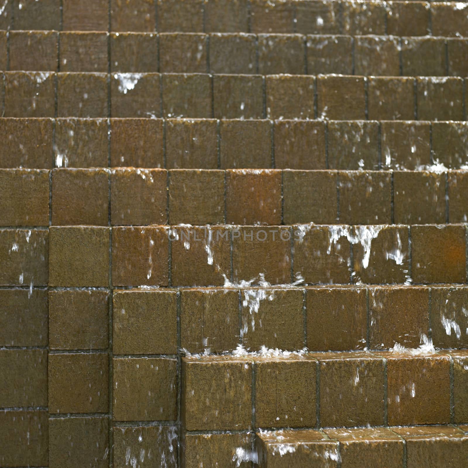 Water falling down on brown bricks