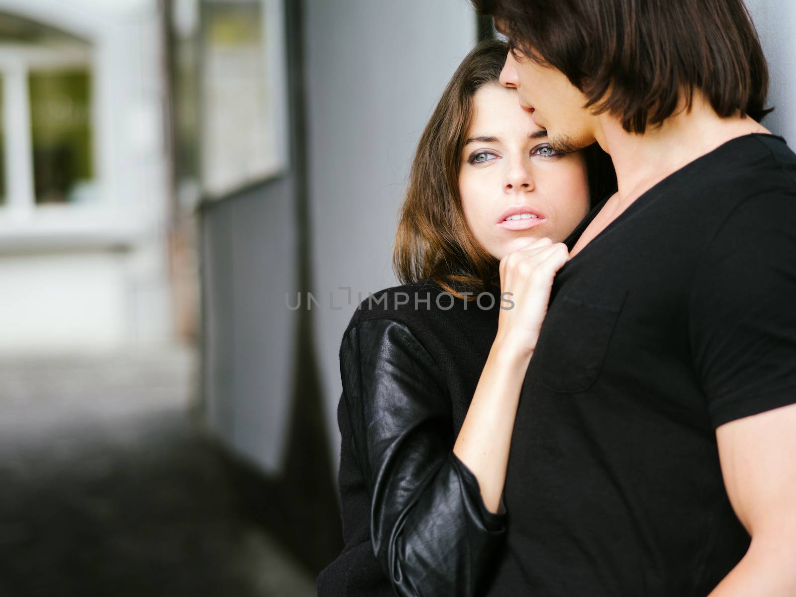 Photo of a young couple in love holding each other in an alley.