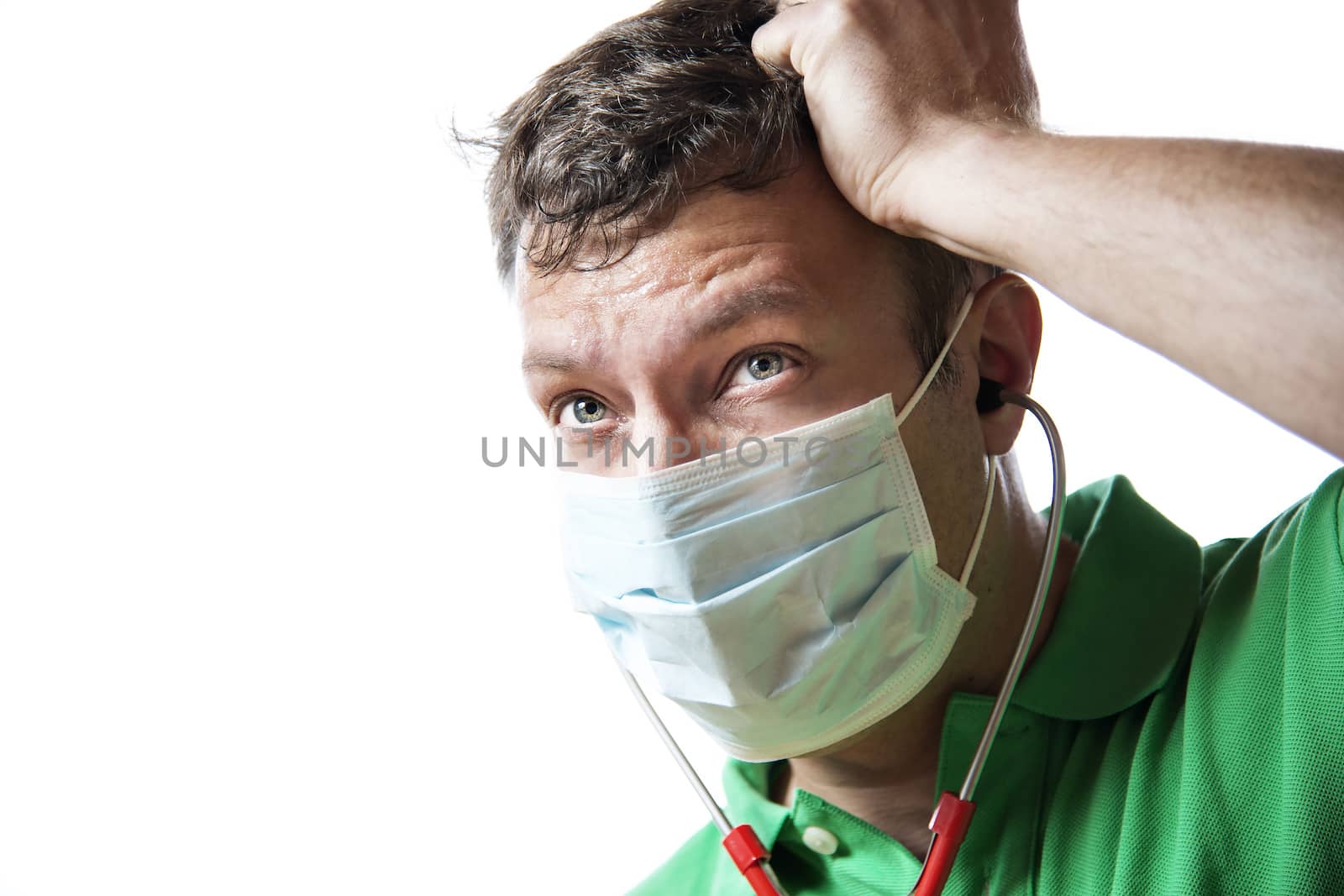 Helpless, anxious and perspiring doctor in a green shirt with a red stethoscope and surgical mask