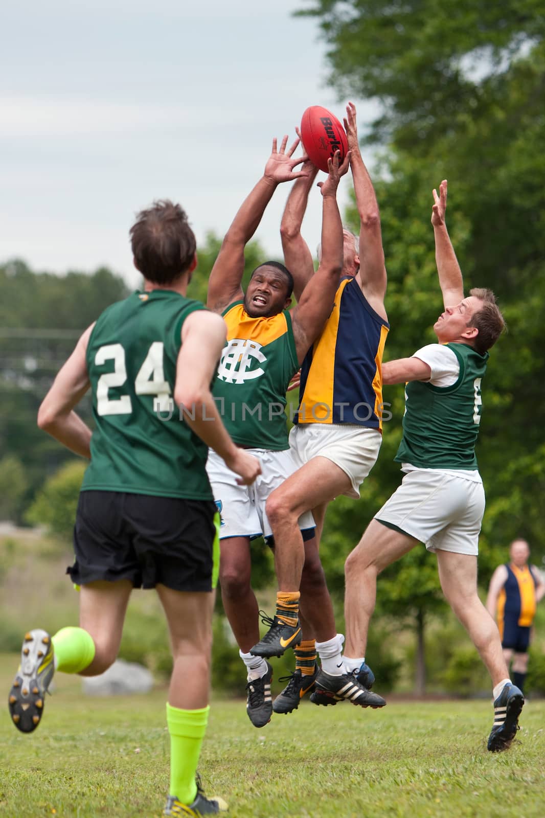 Roswell, GA, USA - May 17, 2014:  Players jump and compete for the ball in an amateur game of Australian Rules Football in a Roswell city park.