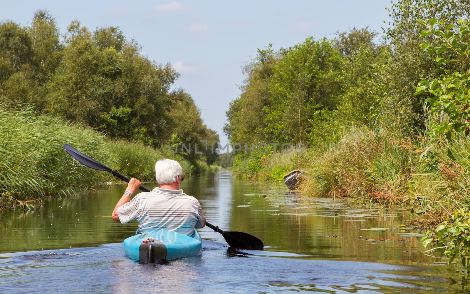 Man paddling in a blue kayak by michaklootwijk