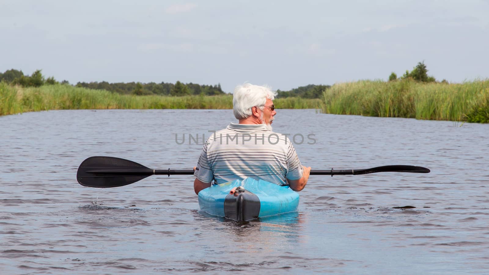 Man paddling in a blue kayak by michaklootwijk