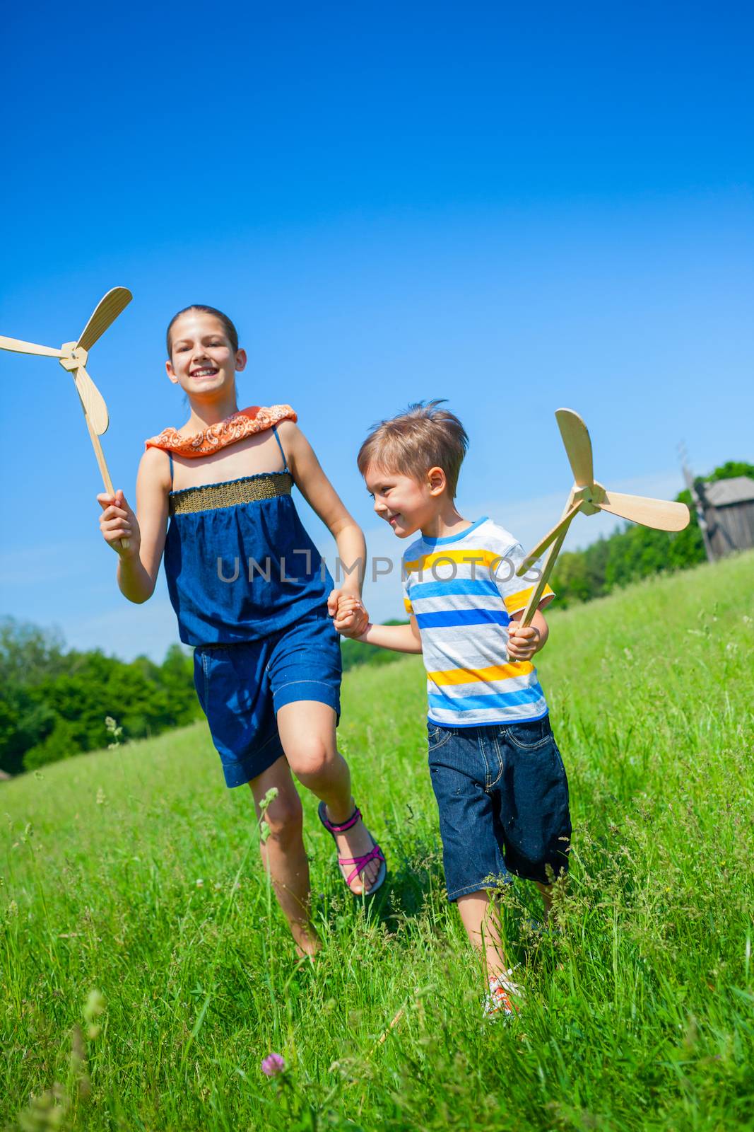 Kids in summer day holds windmill by maxoliki