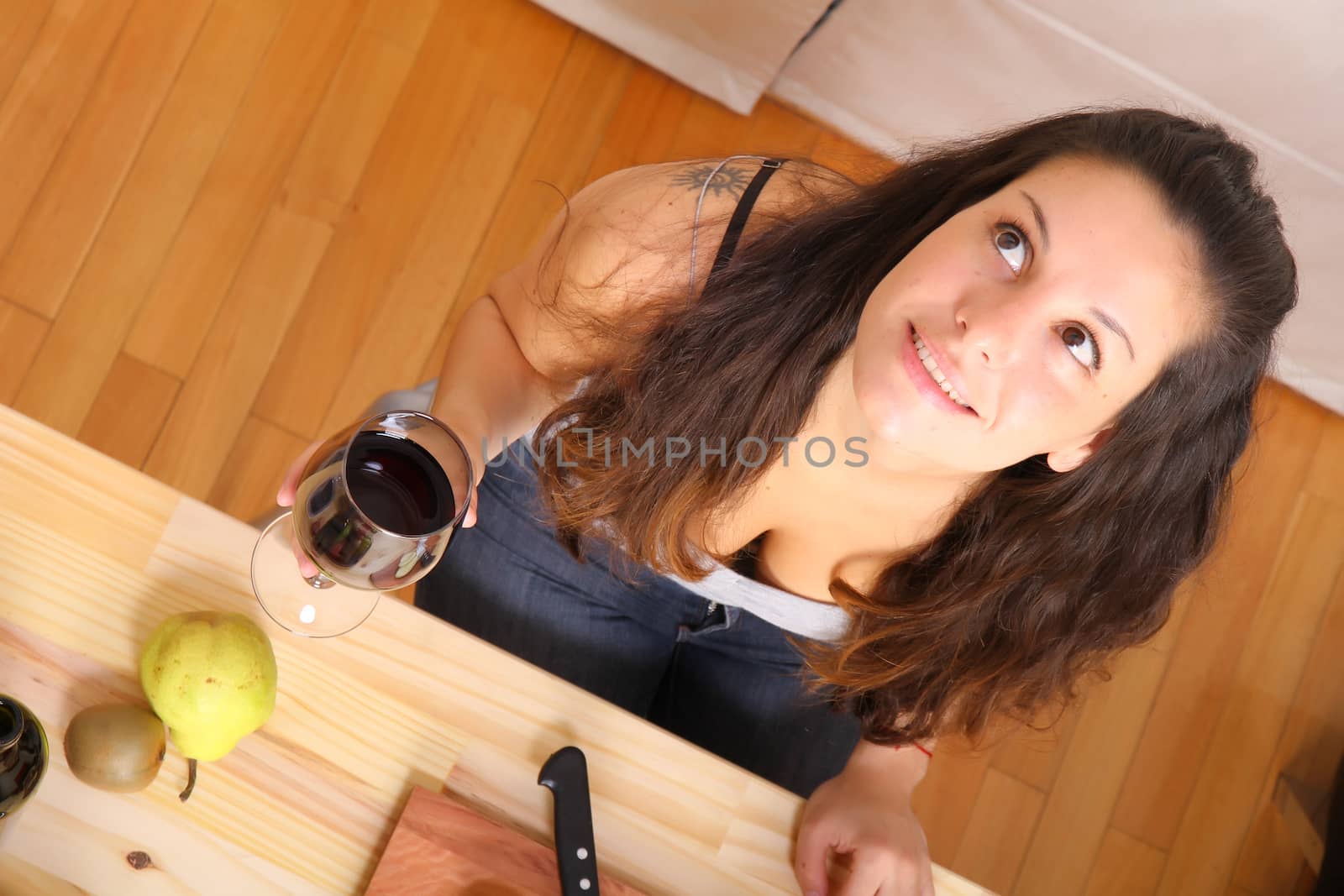 A young adult woman cutting fruits in the kitchen.