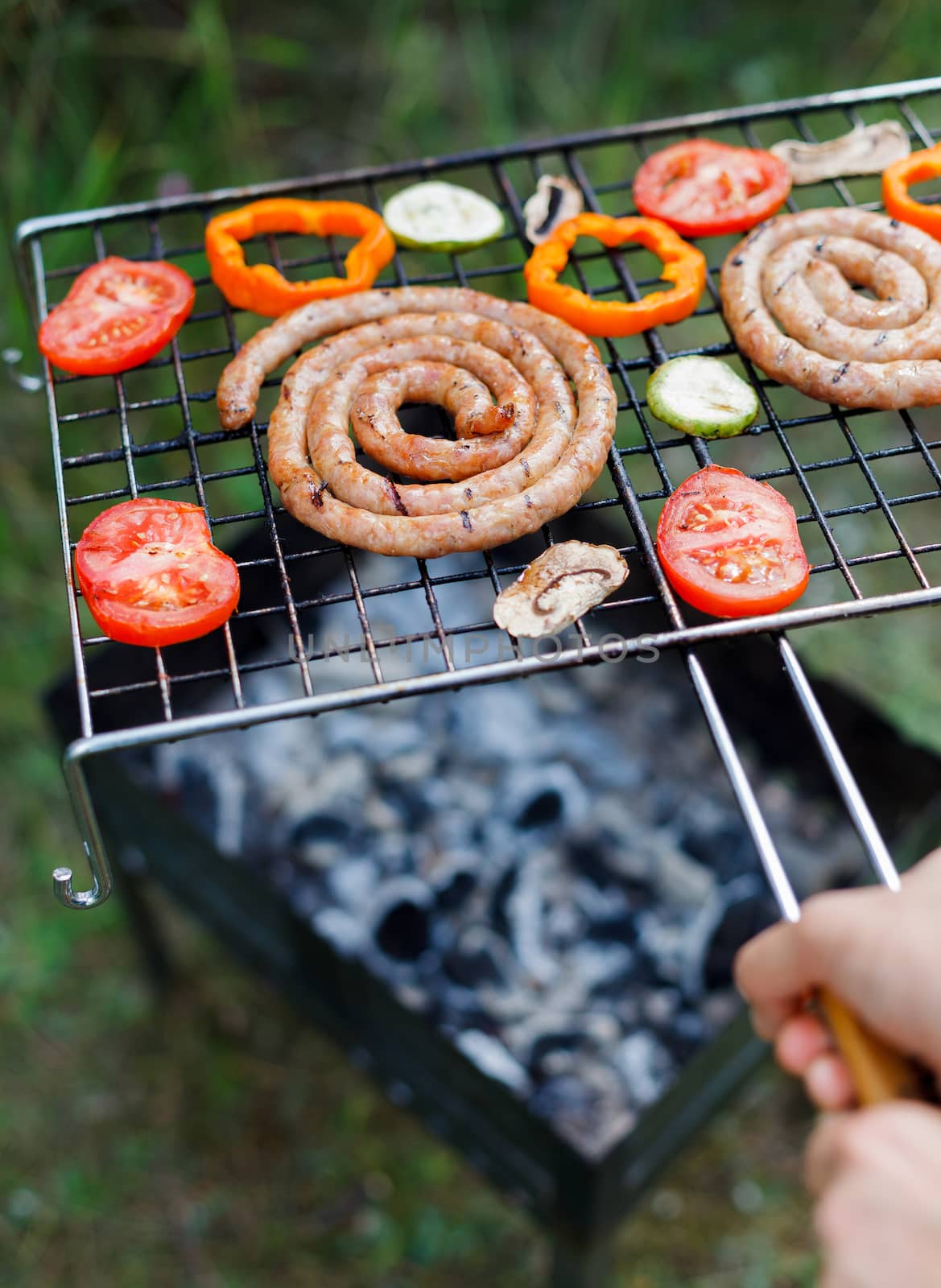 Barbecue on a hot day during the summer vacation on a green grass background. Meat and vegetables on the grill.