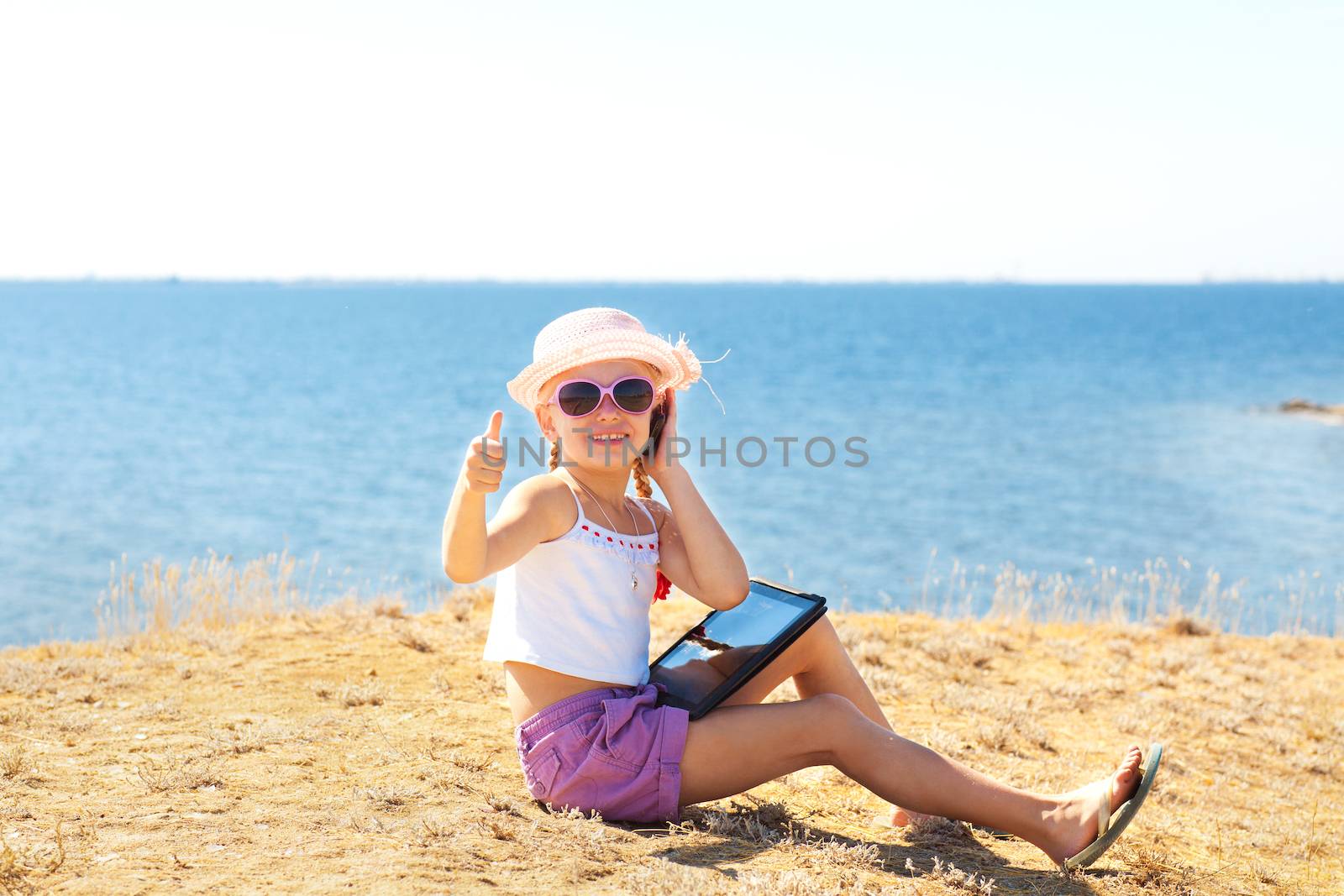 girl on the beach with laptop and phone by vsurkov