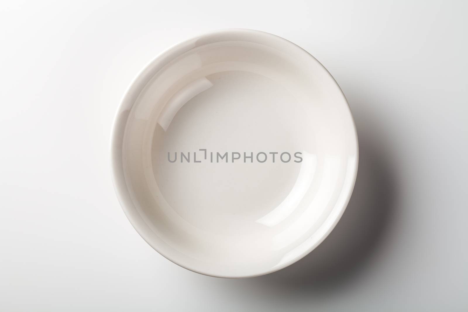 White plate on white background with shadow. Top view 