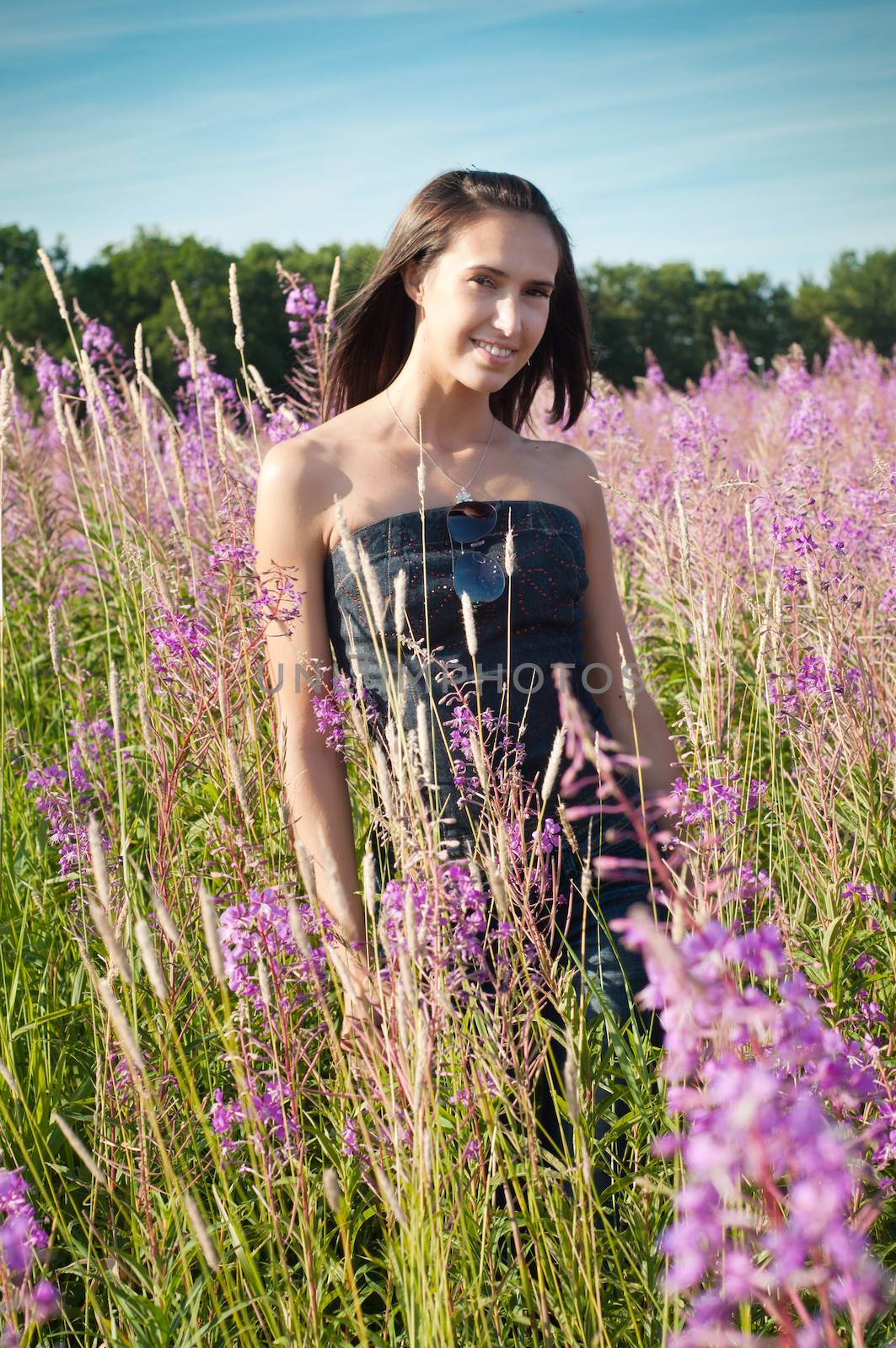 Beautiful young girl on the flowers field