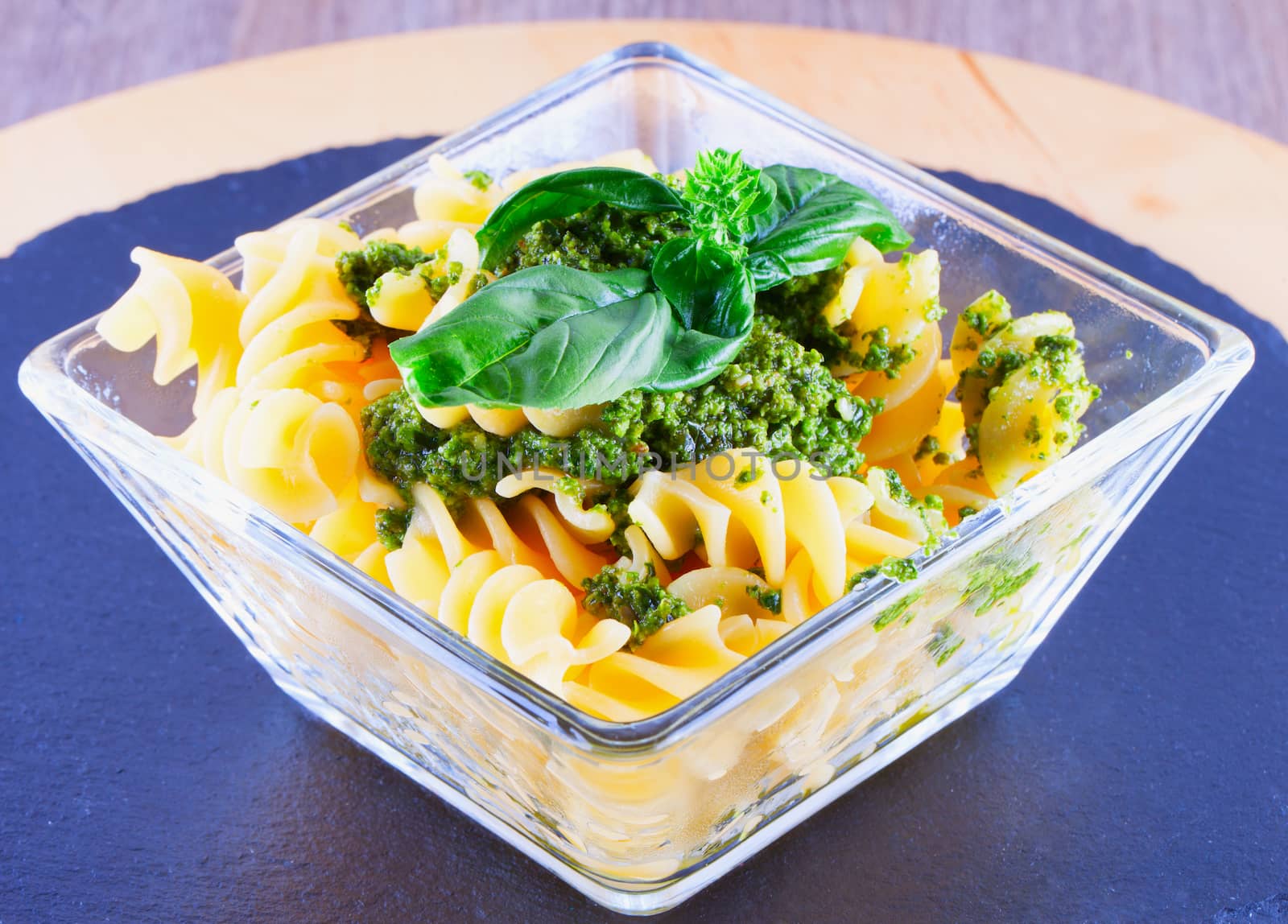 Fusilli al pesto in a square glass over black stone