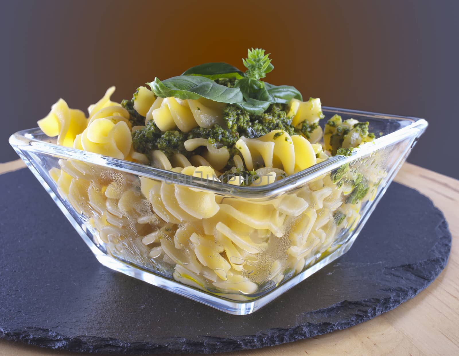 Fusilli al pesto in a square glass over black stone