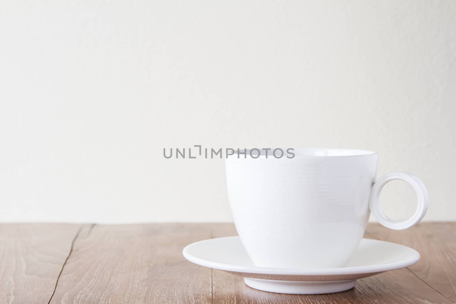 White cup of coffee on wooden table with copyspace area