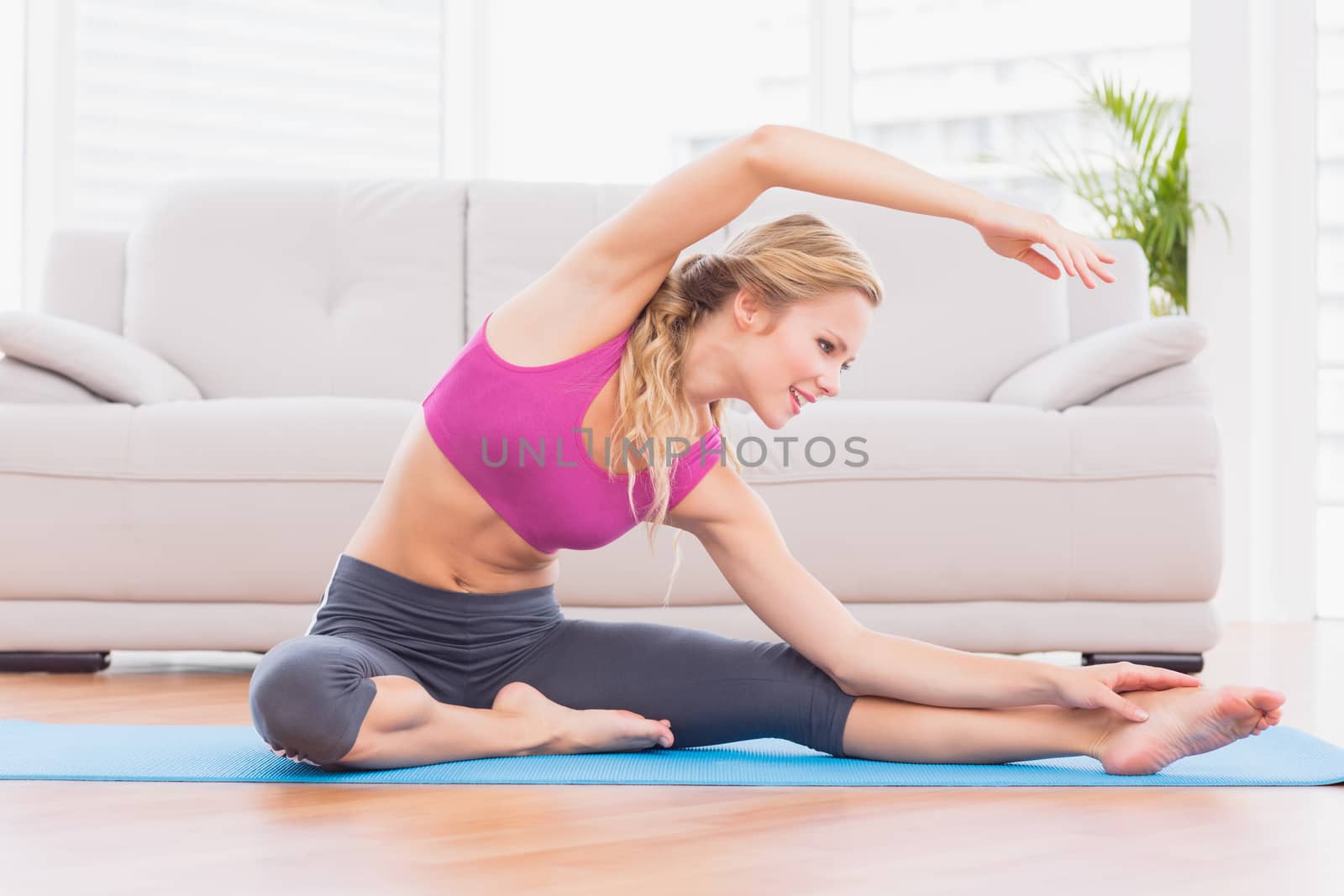 Fit blonde stretching on exercise mat  by Wavebreakmedia