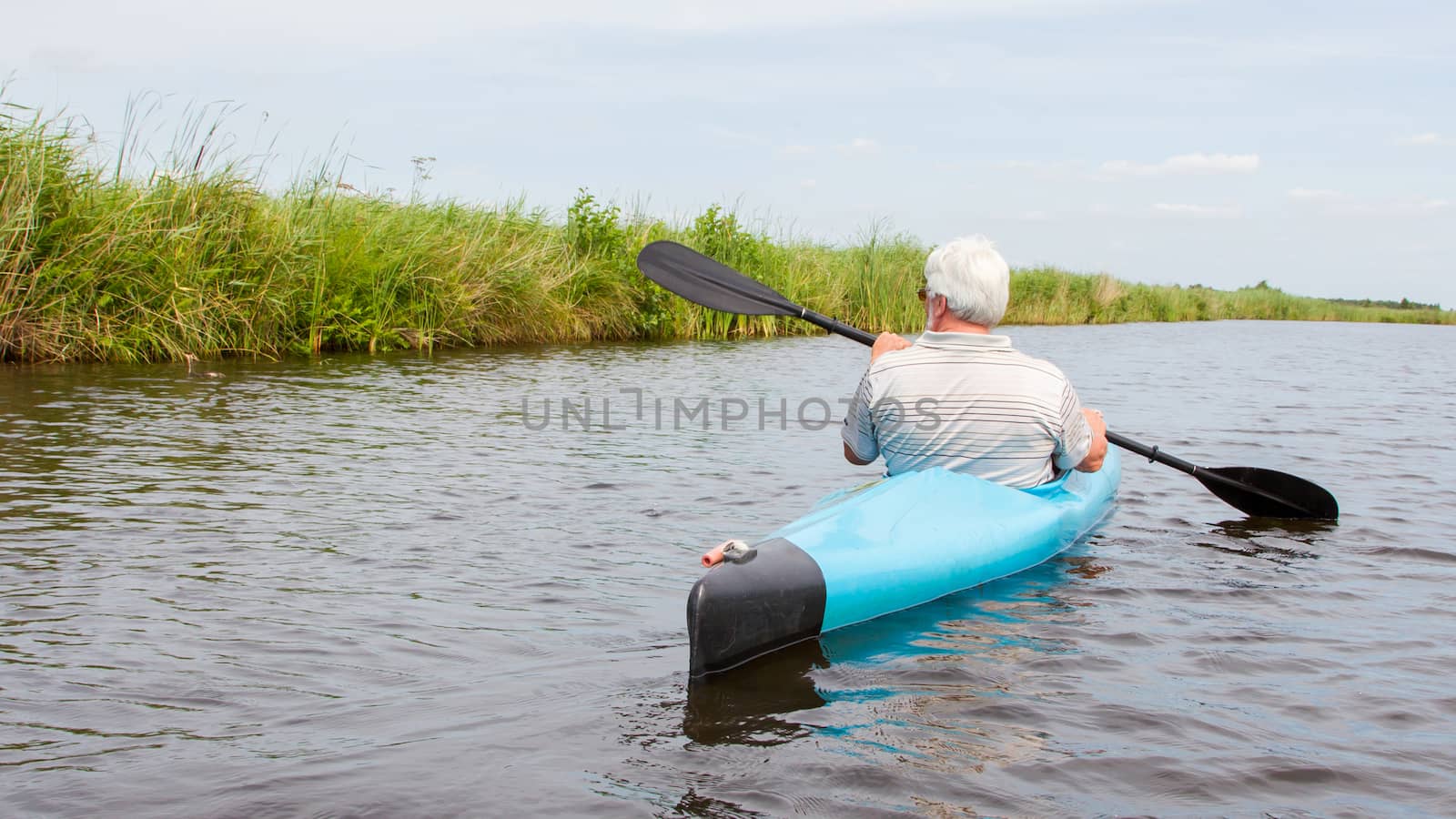 Man paddling in a blue kayak in the Netherlands