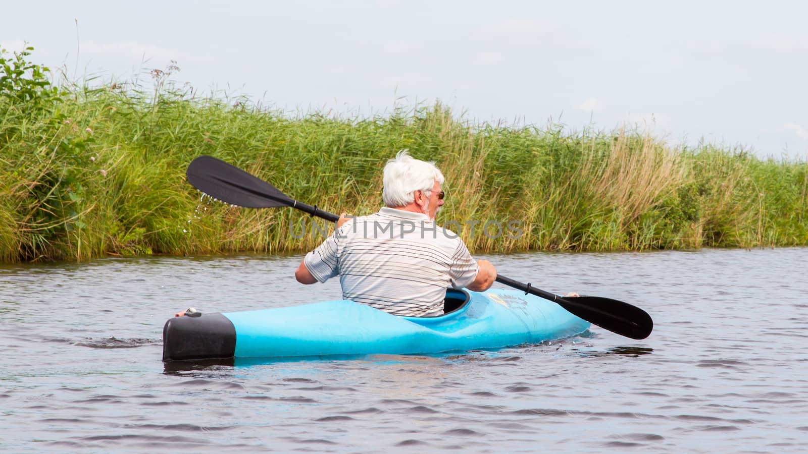 Man paddling in a blue kayak by michaklootwijk