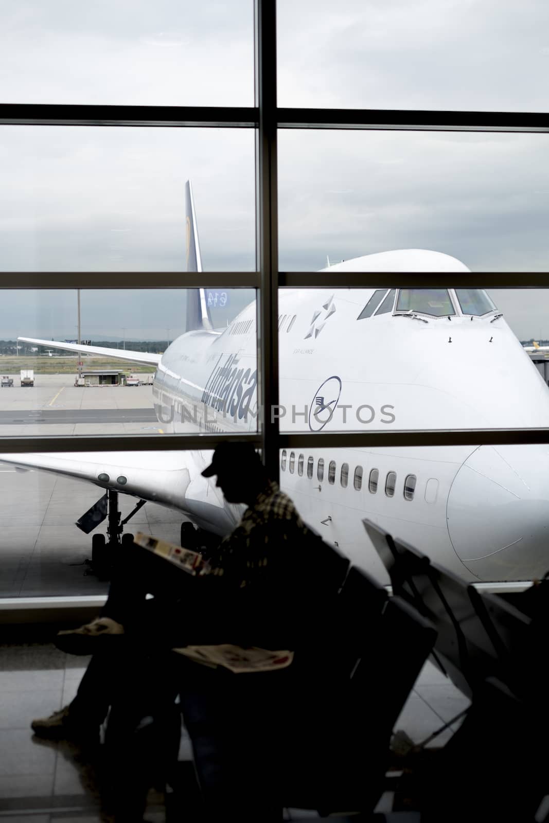FRANKFURT, GERMANY - JULY 21: Silhouette of passenger waiting for flight in terminal with Lufthansa jumbo jet in perspective in the background.. July 21, 2014 in Frankfurt.