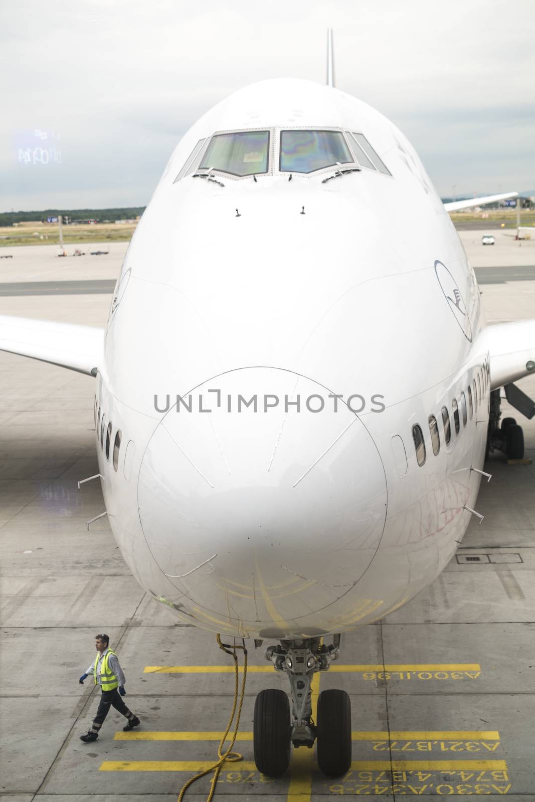 FRANKFURT, GERMANY - JULY 21: Front of Lufthansa jumbo jet on the ground in perspective , with airport employee walking past. July 21, 2014 in Frankfurt.