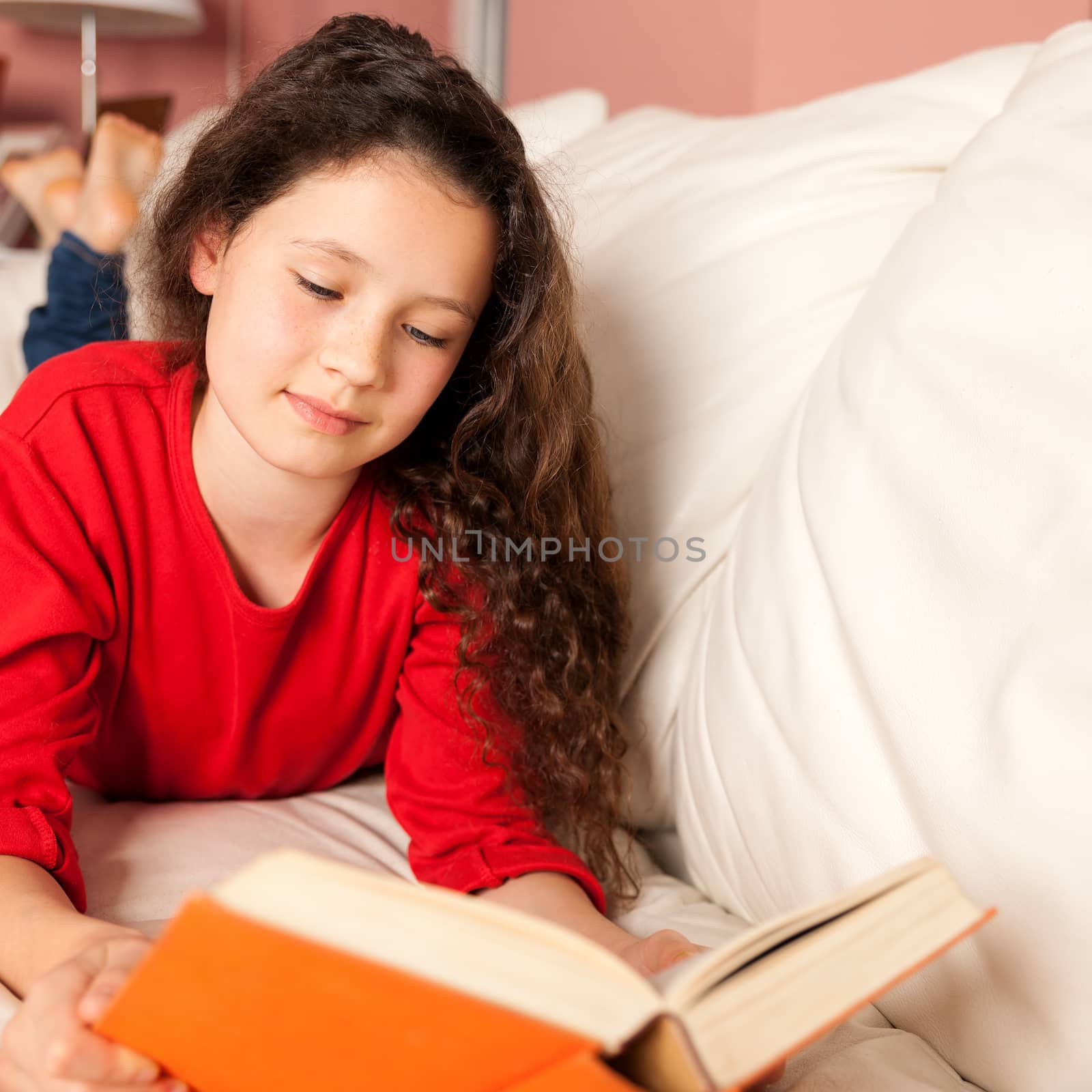 An image of a girl with a book on the sofa