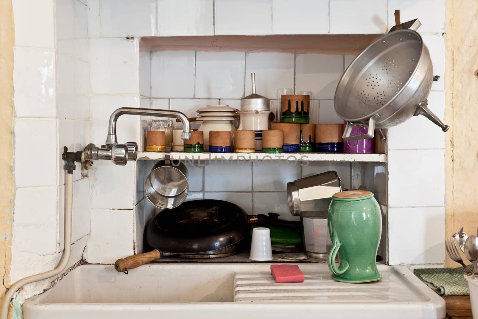 Sink of an old italian kitchen with pan, saucers and cups