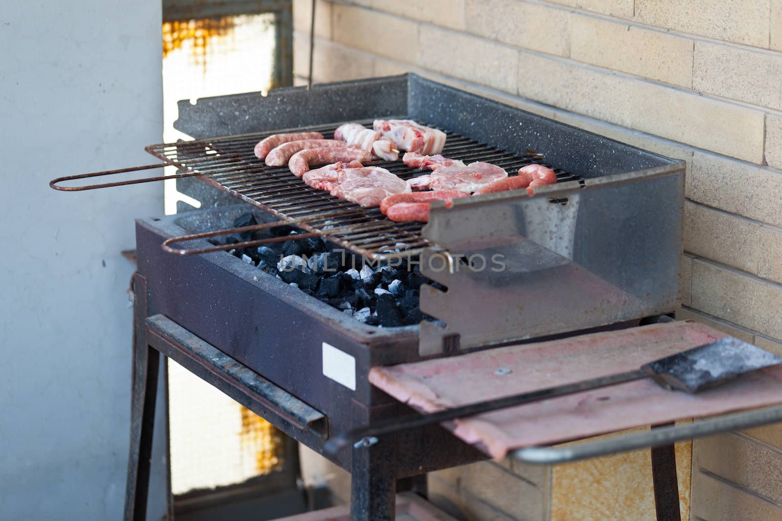 Several type of meats being cooked on a barbecue