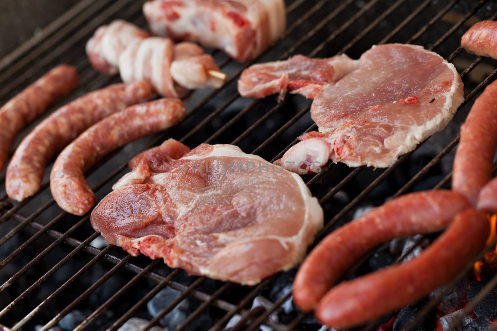 Several type of meats being cooked on a barbecue