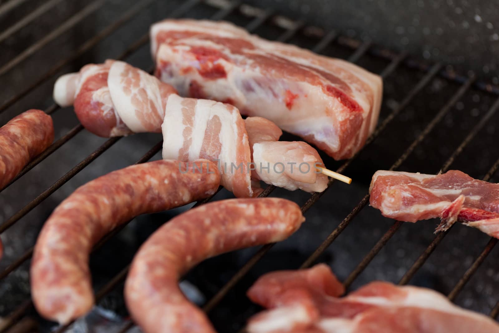 Several type of meats being cooked on a barbecue